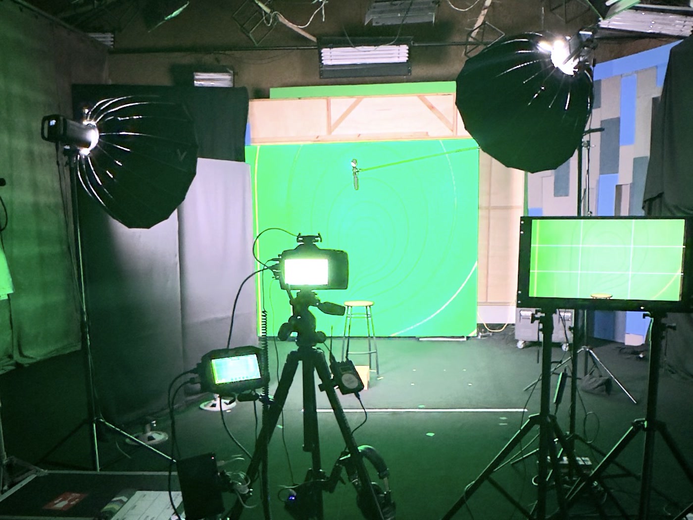 Estúdio de green screen montado, com luzes, câmera e monitor de referência